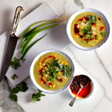 Two bowls of soup with garnishes on a marble surface