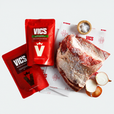 Red Vics seasoning packets with a piece of raw meat and onions on a white background