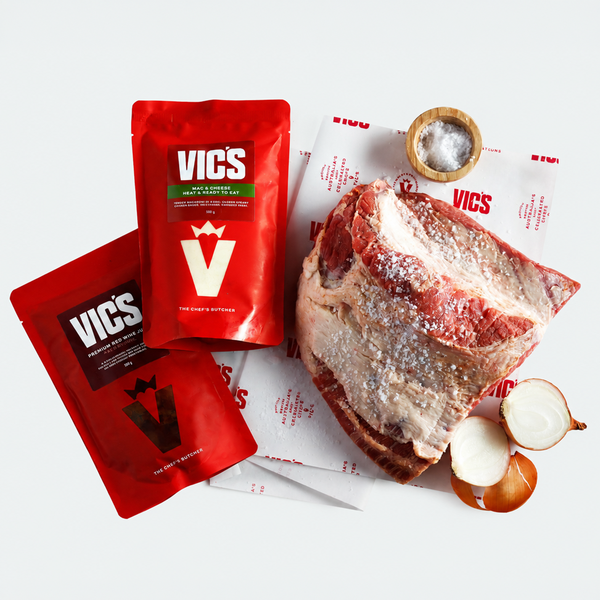 Red Vics seasoning packets with a piece of raw meat and onions on a white background