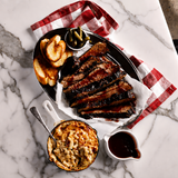 Plated meal with steak, baked beans, and bread on a marble surface